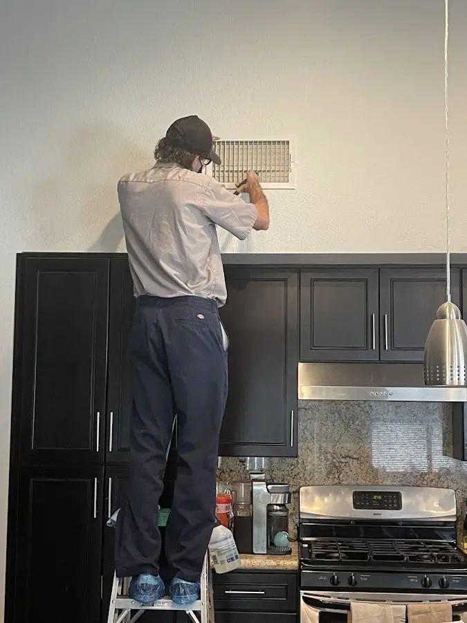 Technician inspecting an air vent during HVAC service in Oak Lawn